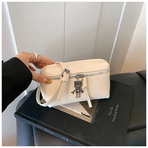 Detail of a mini cream square bag with a unique silver robot pendant and zip closure