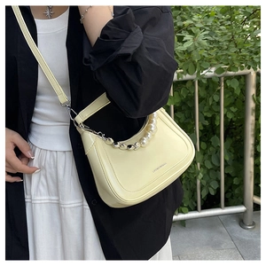 Détail du sac bandoulière jaune nacré avec chaînes décoratives en perles et métal argenté