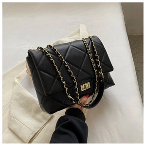 Close-up of black quilted crossbody bag with gold chain strap and metal turn-lock