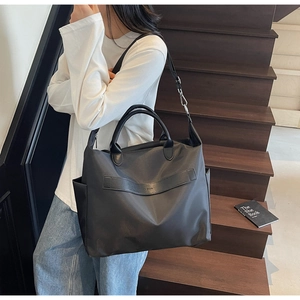 Détail du grand sac cabas noir avec logo NODO, garniture en cuir et poche latérale
