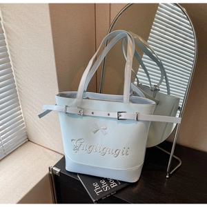 Détail du sac cabas bleu clair avec nœud blanc, broderie et boucle de ceinture en cuir