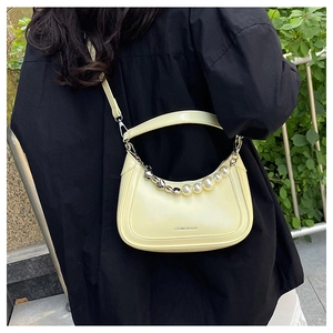 Détail de la chaîne perle et cœur sur un sac à main demi-lune jaune en cuir souple
