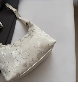 Detail of cream-colored jacquard shoulder bag featuring butterfly texture and silver studs