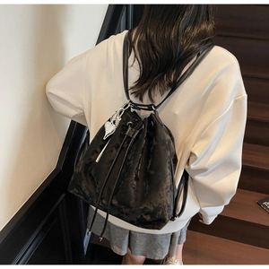 Detail of black drawstring bucket backpack with silver heart charm and cloud-like texture