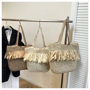 Detail of bohemian straw tote bags with long layered tassels in three natural colors
