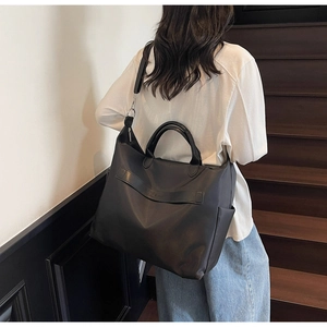 Détail d'un sac cabas noir en toile avec large bandoulière et finitions en cuir