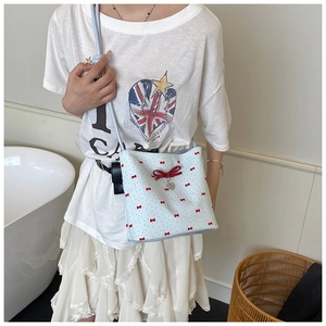 Detail of light blue bucket bag featuring red bow patterns and heart-shaped pendant