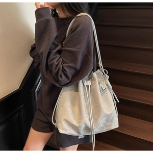 Silver-grey bucket bag with butterfly charm on a wooden staircase backdrop