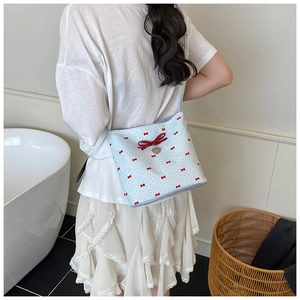 Close-up of a light blue bow shoulder bag featuring red ribbons and a heart charm