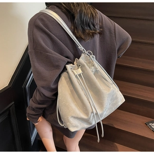 Detail of silver drawstring bucket bag with metallic texture and butterfly charm decoration