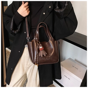 Detail of dark brown vintage faux leather tote with embossed letters and a bear charm