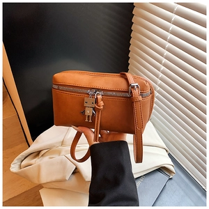 Close-up of brown mini crossbody box bag with unique silver robot metal keychain detail