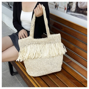 Close-up of cream handmade woven tote bag with fringe details and natural straw texture