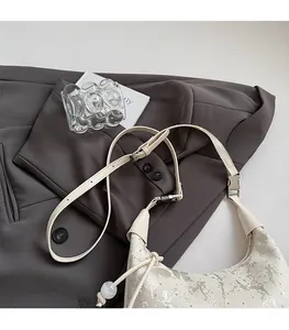 Detail of creamy white crescent bag with silver foil texture and adjustable strap