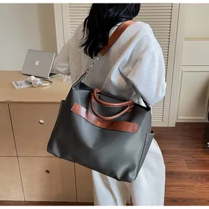 Détail d'un grand sac fourre-tout gris en toile avec des lanières en cuir marron