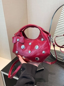 Sac seau rouge en cuir verni avec clous argentés et nœuds décoratifs latéraux