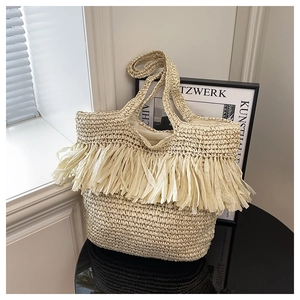 Detail of hand-woven straw tote bag with long tassels and spacious fabric lining