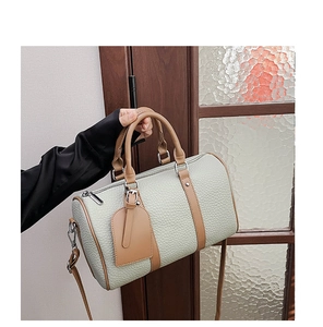 Detail of trendy Boston bag with pale green pebble leather and brown strap handles