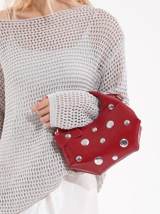 Sac à bandoulière rouge brillant avec clous argentés et nœud sur fond blanc minimaliste