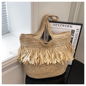 Detailed close-up of woven straw tote bag with bohemian fringe and soft natural lighting
