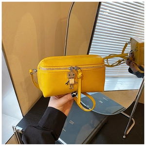 Detail view of a bright yellow mini box bag with silver robot charm and zipper