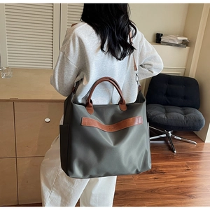 Détail du sac cabas en nylon vert armée avec poignées en cuir marron et poche latérale