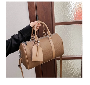 Detail of a brown lychee pattern leather bowling bag with silver zipper and luggage tag