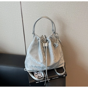 Close-up of silver-grey bucket bag with velvet texture, drawstring and heart charm