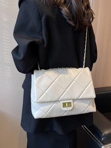Chic beige quilted chain crossbody bag styled with a professional black blazer suit