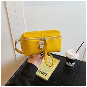 Detail of yellow mini square crossbody bag featuring a silver robot charm and metal zipper