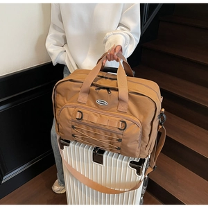 Brown nylon travel bag shown secured to a suitcase handle for easy luggage carrying