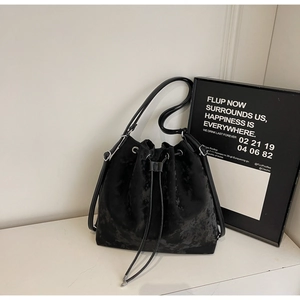 Detail of black drawstring bucket bag with moiré velvet texture and silver metal buckles