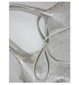 Close-up of silver jacquard texture with sparkling rhinestones and leather knot detail