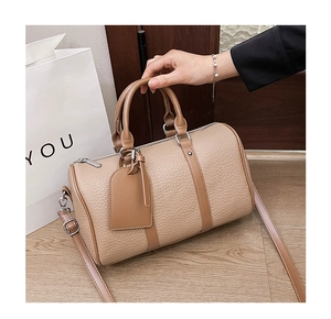 Detail of beige lychee grain leather boston bag with brown handles and detachable strap