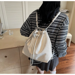 Detail of white minimalist bucket bag showing soft leather texture and heart charm on a model