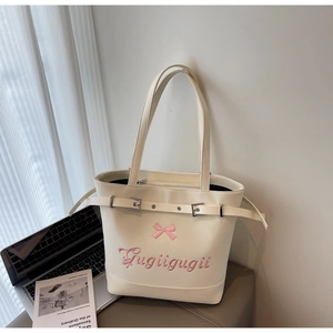 Détail d'un cabas crème avec broderie de nœud rose et inscription Gugiigugii élégante