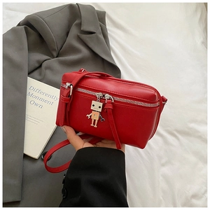 Detail shot of a red mini box bag with a unique robot charm and smooth PU leather texture