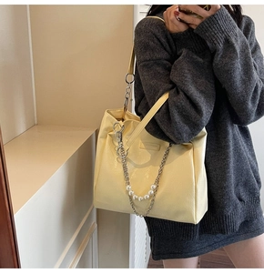 Detail of light yellow tote bag with textured PU leather and pearl metal chain strap