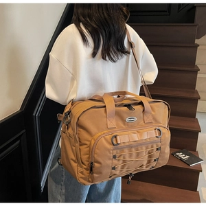 Detail of a brown large capacity travel bag with MOCOBAG logo on a wooden staircase