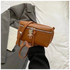 Detail of small brown crossbody bag featuring silver zipper and robot metal charm