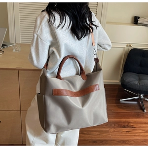 Détail du sac fourre-tout en nylon kaki avec poignées en cuir et bandoulière amovible