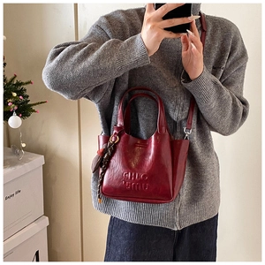 Detail view of burgundy leather handbag featuring embossed lettering and metal strap clips