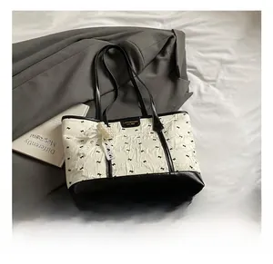 Detail einer zweifarbigen Tote Bag mit Falten und dekorativem Perlenspitzanhänger