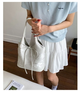 Close-up of white bucket bag featuring butterfly print and decorative bow on wood floor