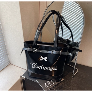 Détail du sac cabas en cuir verni noir avec nœud blanc et boucle argentée élégante
