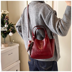 Detail view of wine red leather handbag with top handles and logo embossing