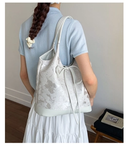 Detail view of large white tote bag featuring grey butterfly prints and ribbon bow detail