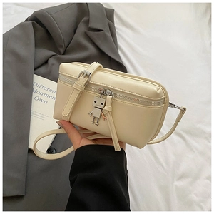 Detail of creamy white crossbody mini box bag with silver robot charm and adjustable strap