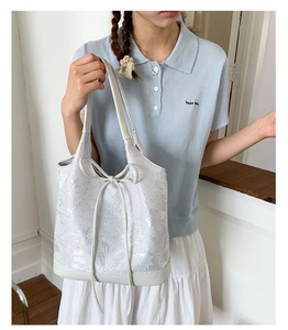 Close-up of white tote bag featuring butterfly embossed texture and delicate bow details