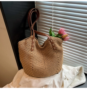 Détail du tissage en paille en forme de V et des anses en cuir marron du sac cabas
